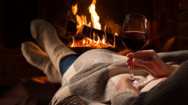 Woman enjoying a glass of red wine and a cosy night by the fire - autumn and winter breaks in Enniskillen Fermanagh - november breaks enniskillen