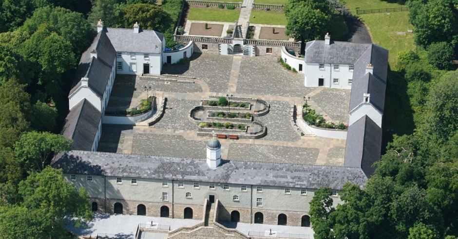 Aerial view of Castle Archdale courtyard and historic buildings surrounded by woodland in County Fermanagh
