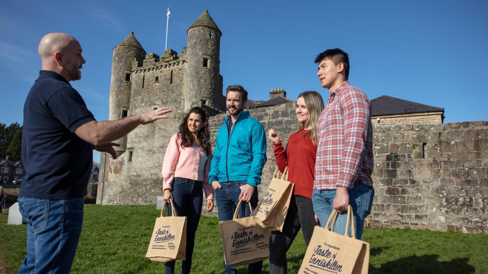 Group enjoying the Enniskillen Taste Experience tour outside Enniskillen Castle with local guide and shopping bags