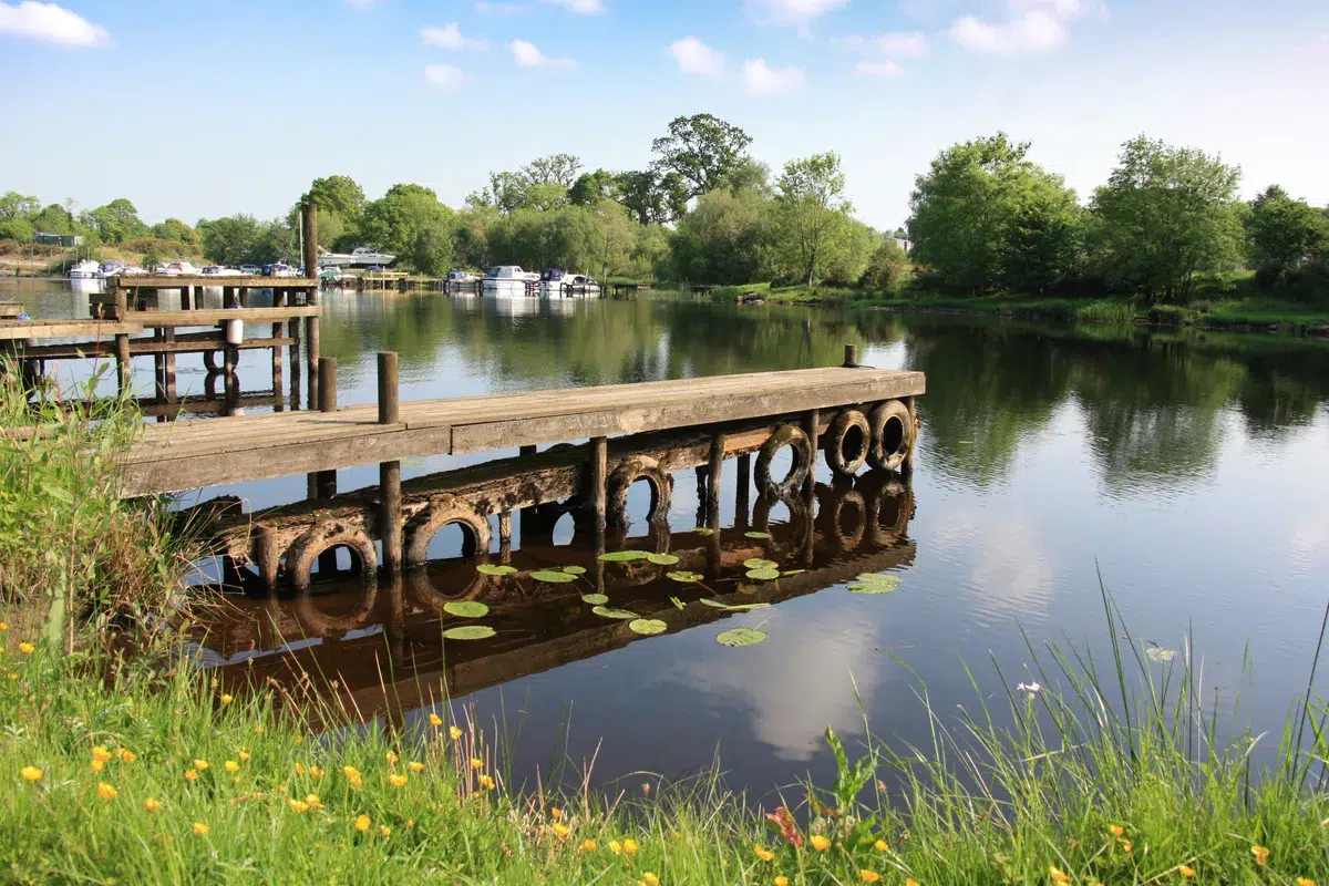 Wooden jetty on the calm waters of Lough Erne near Enniskillen with boats and green countryside in the background Enniskillen Scenic Spots