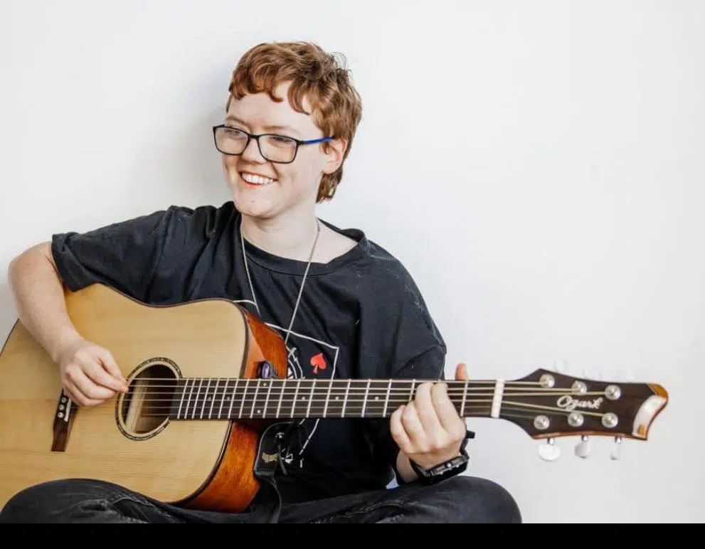 Keisha Maguire playing acoustic guitar during a live music performance