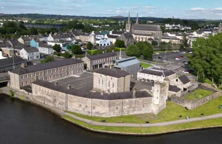 Aerial view of Enniskillen Castle beside the River Erne with surrounding town buildings and church in the background