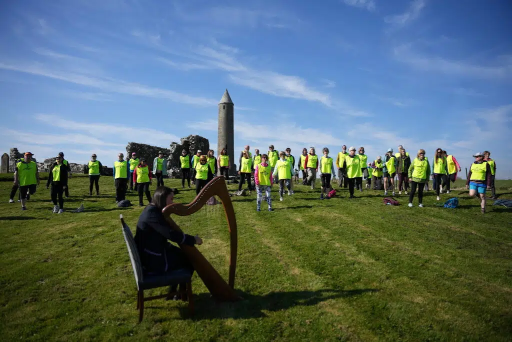 Participants gathered at Devenish Island during the Fermanagh Camino with harp performance beside the historic round tower.