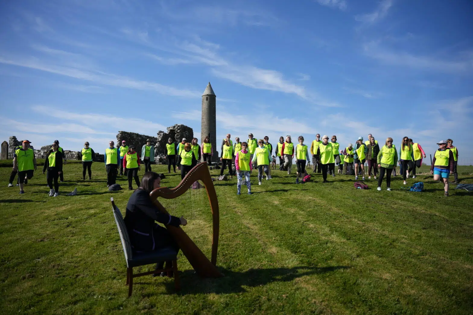 Participants gathered at Devenish Island during the Fermanagh Camino with harp performance beside the historic round tower.