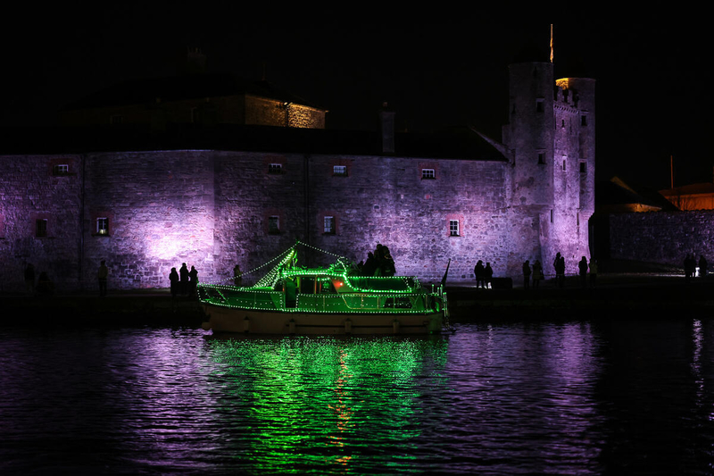 Illuminated boat passing Enniskillen Castle on the River Erne, Enniskillen, County Fermanagh.