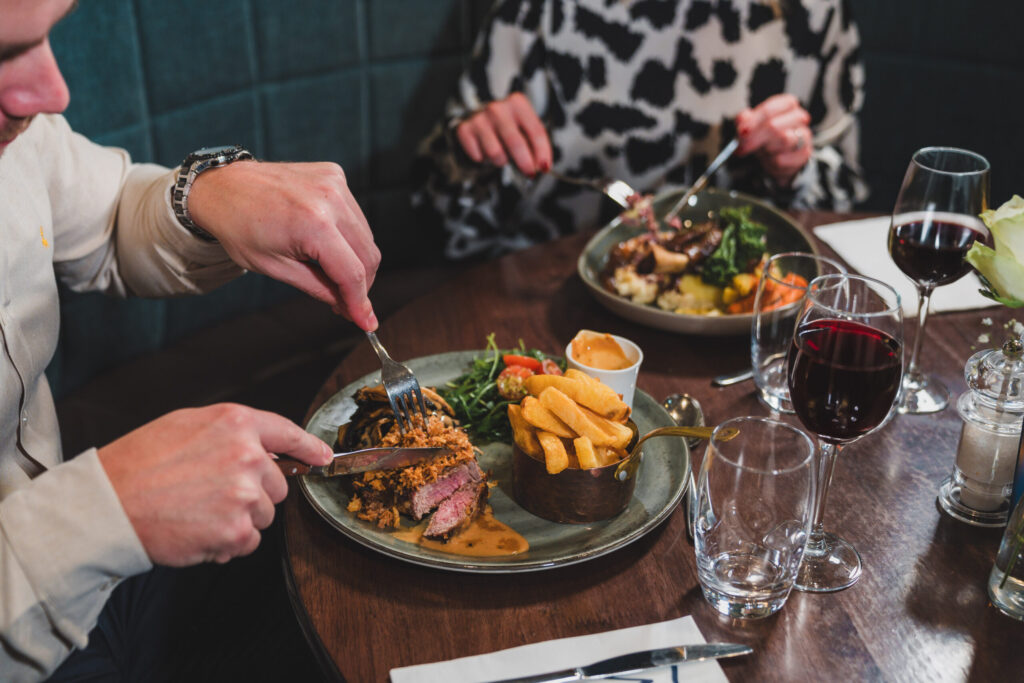 Guests enjoying a wine and dine experience with steak dinner and red wine at the Westville Hotel restaurant in Enniskillen. christmas dining enniskillen