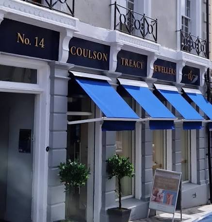 A jewellery shop named Coulson Treacy Jewellers at No. 14, with blue awnings and potted plants outside the entrance.