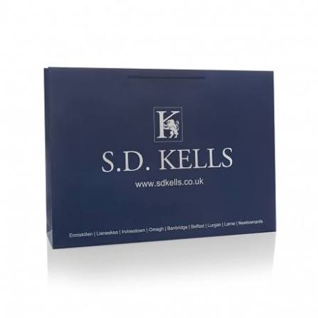 A blue shopping bag with the S.D. Kells logo, website, and shop locations printed in white text.