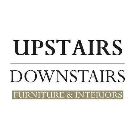 A logo with the words "UPSTAIRS DOWNSTAIRS" in black text and "FURNITURE & INTERIORS" in white text on a greenish-brown background.